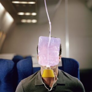 Man with oxygen mask hanging in front of face, on airliner